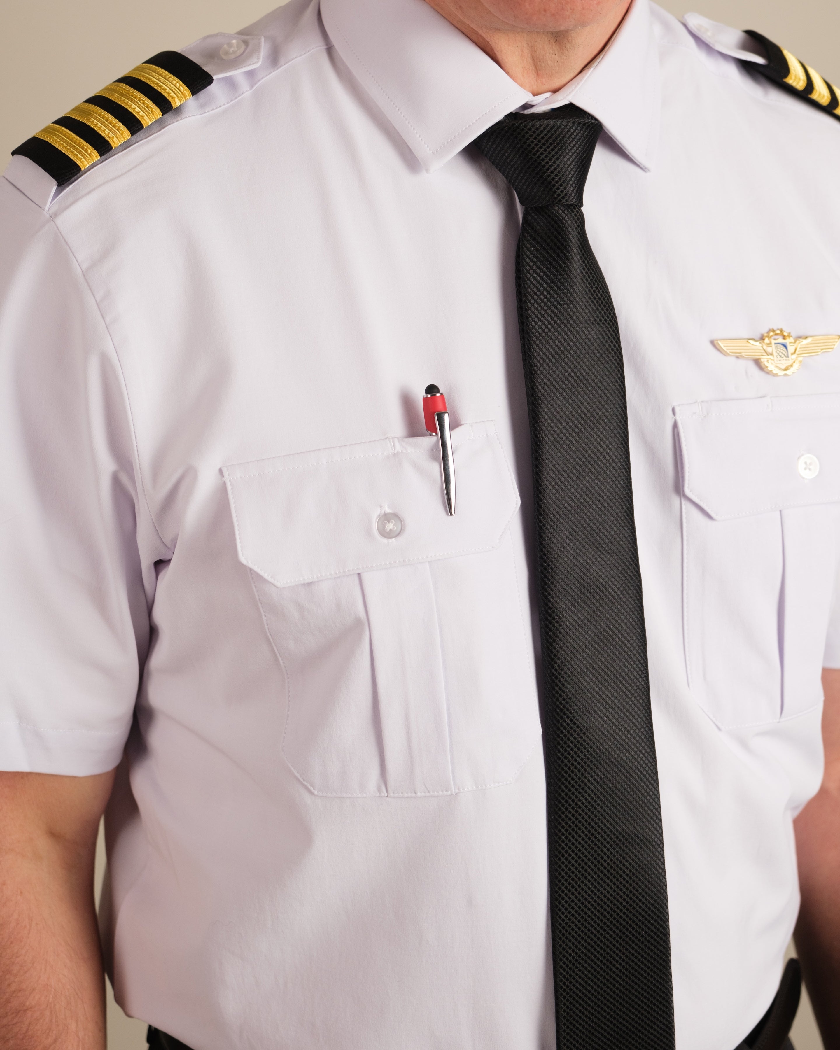 Close-up of pilot wearing Cloud Cotton uniform shirt with tie, wings badge, and pen in chest pocket